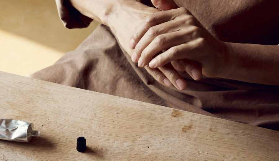 Gentle hand massage with natural skincare, wooden table, silver tube, mindful self-care ritual