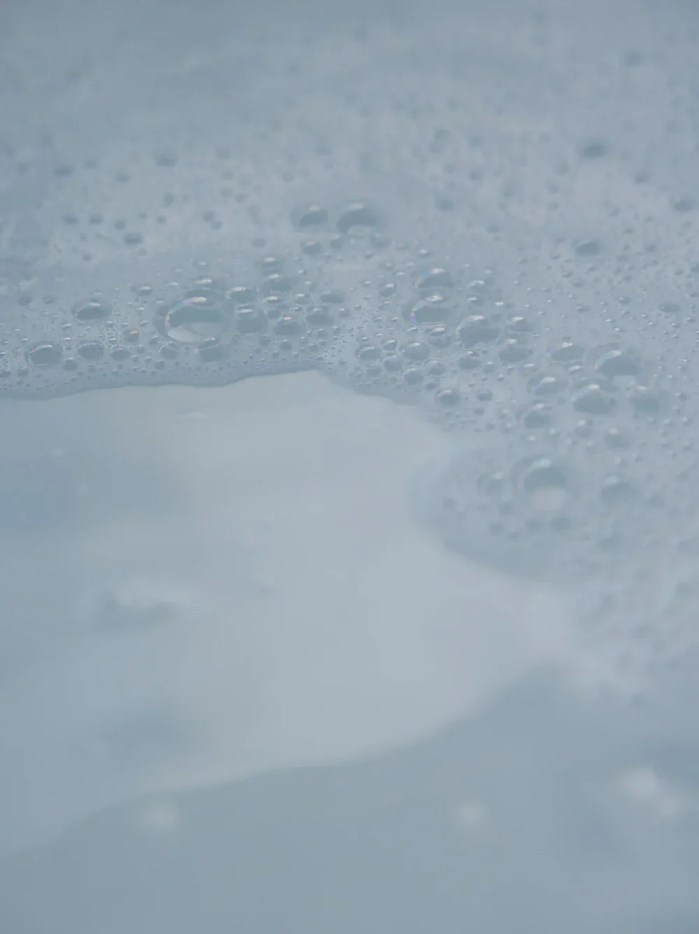 Gentle foam bubbles on calm water surface, evoking mindful self-care rituals