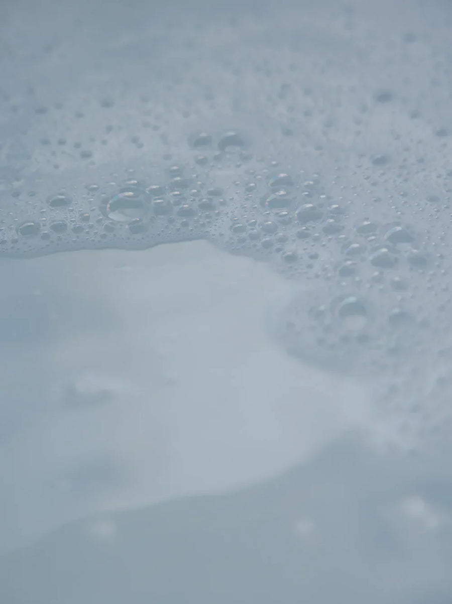 Gentle foam bubbles on calm water surface, evoking mindful self-care rituals
