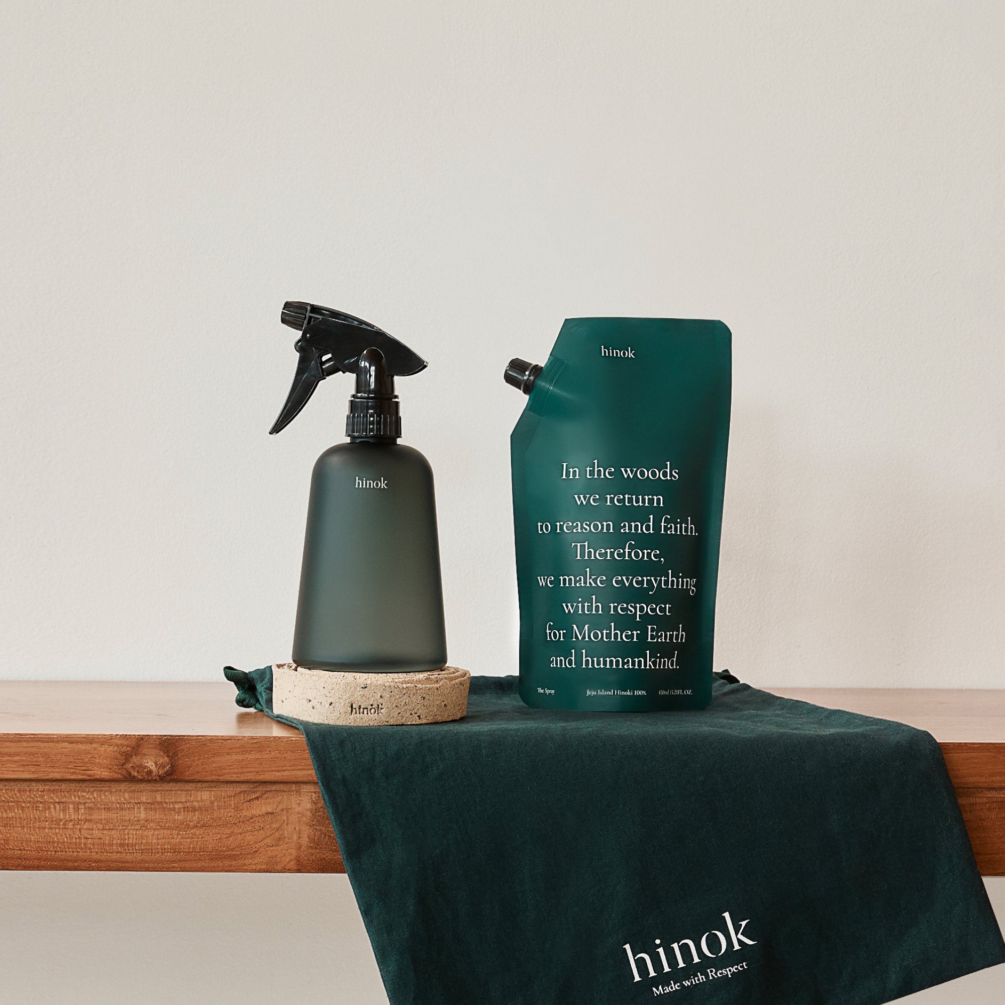 The Spray bottle and refill pouch on a wooden bench