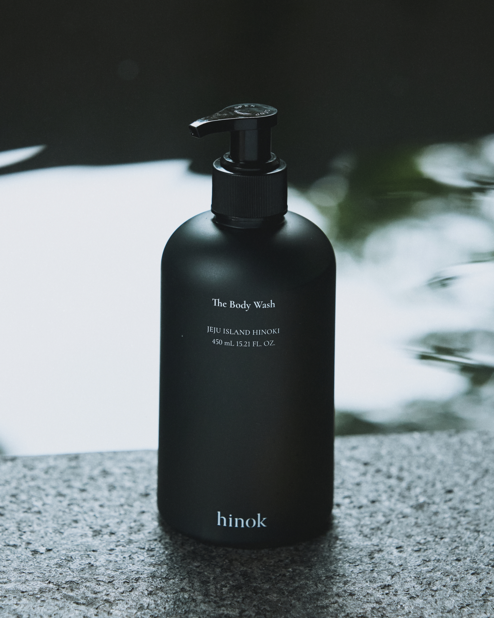 The Body Wash bottle with water droplets on stone
