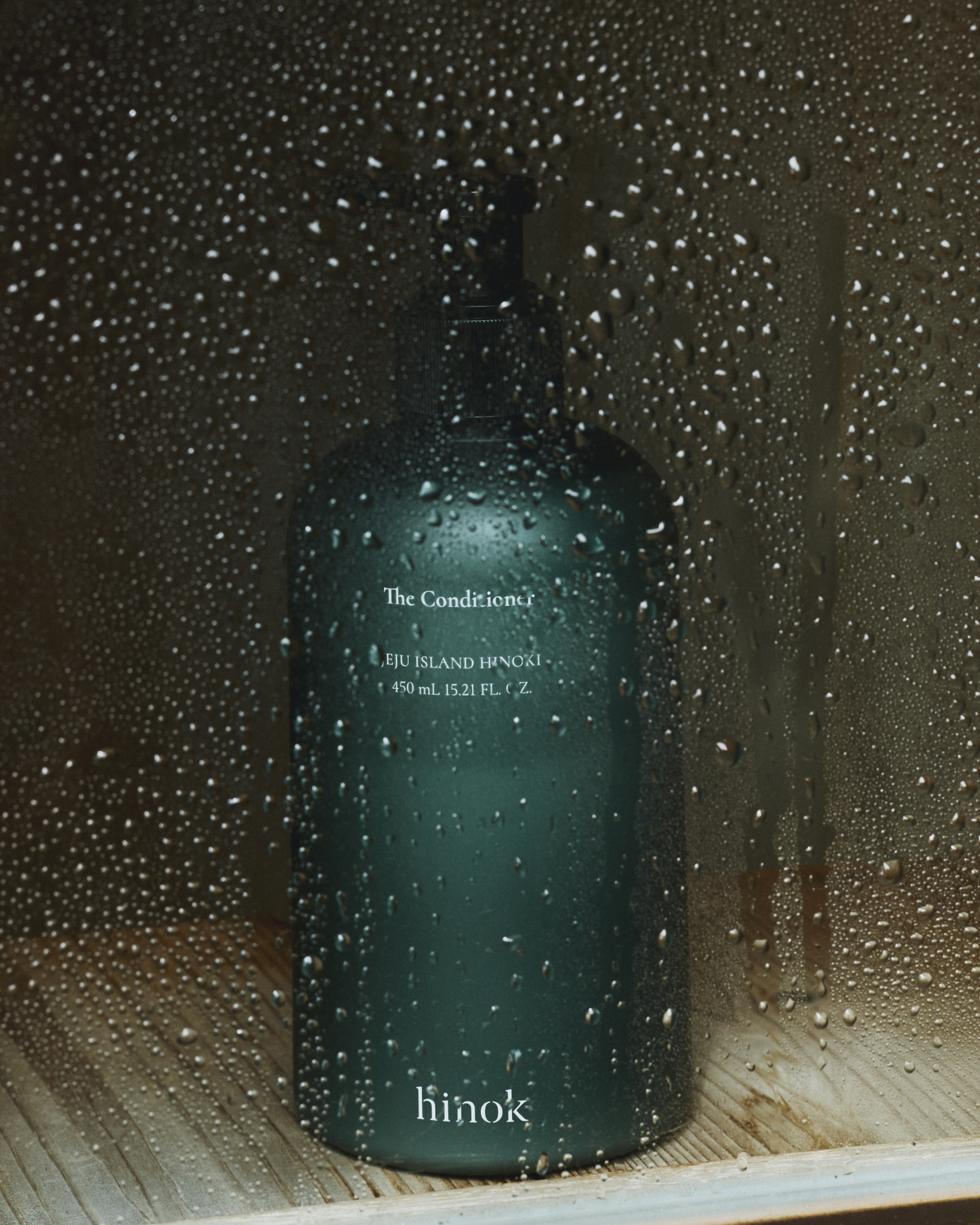 The Conditioner bottle behind water-beaded glass