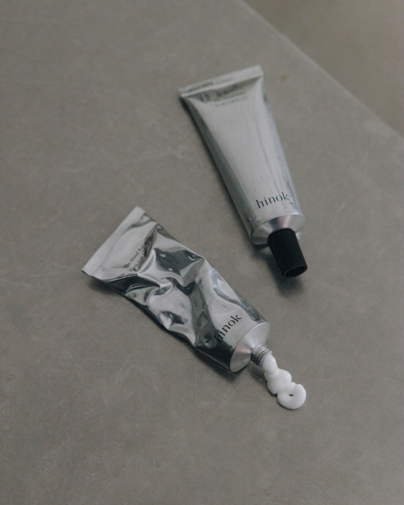 The Hand Balm tube with water droplets on stone