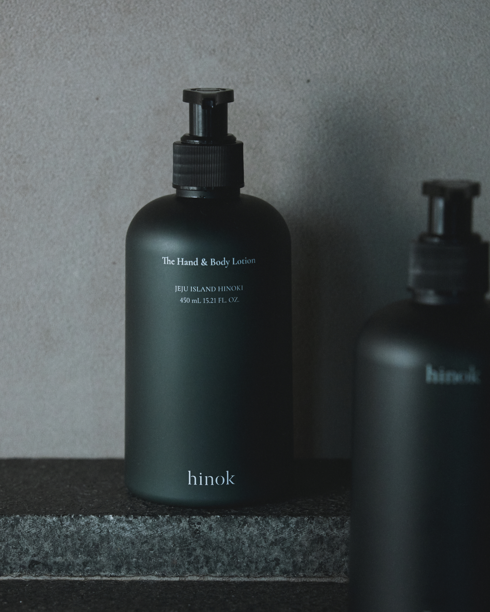 The Hand and Body Lotion bottle with water droplets on stone