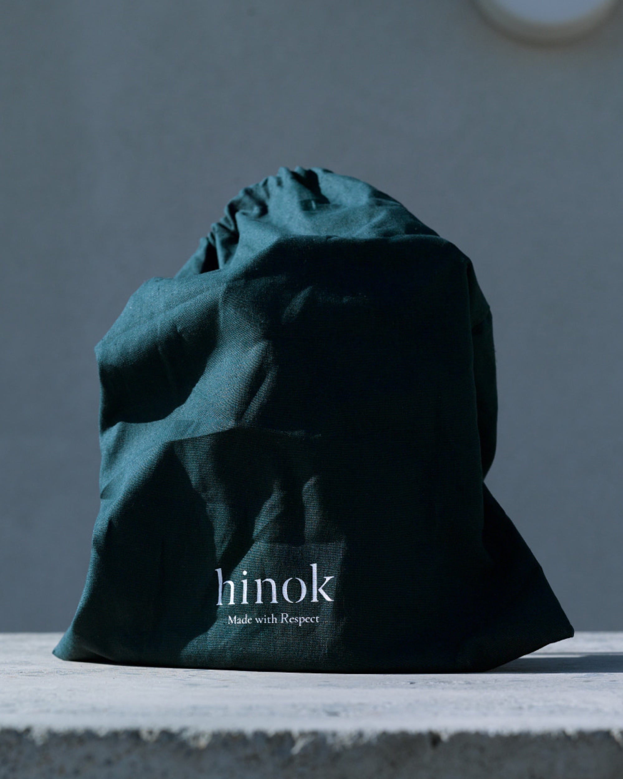 Dark green Hinok linen pouch on a stone ledge
