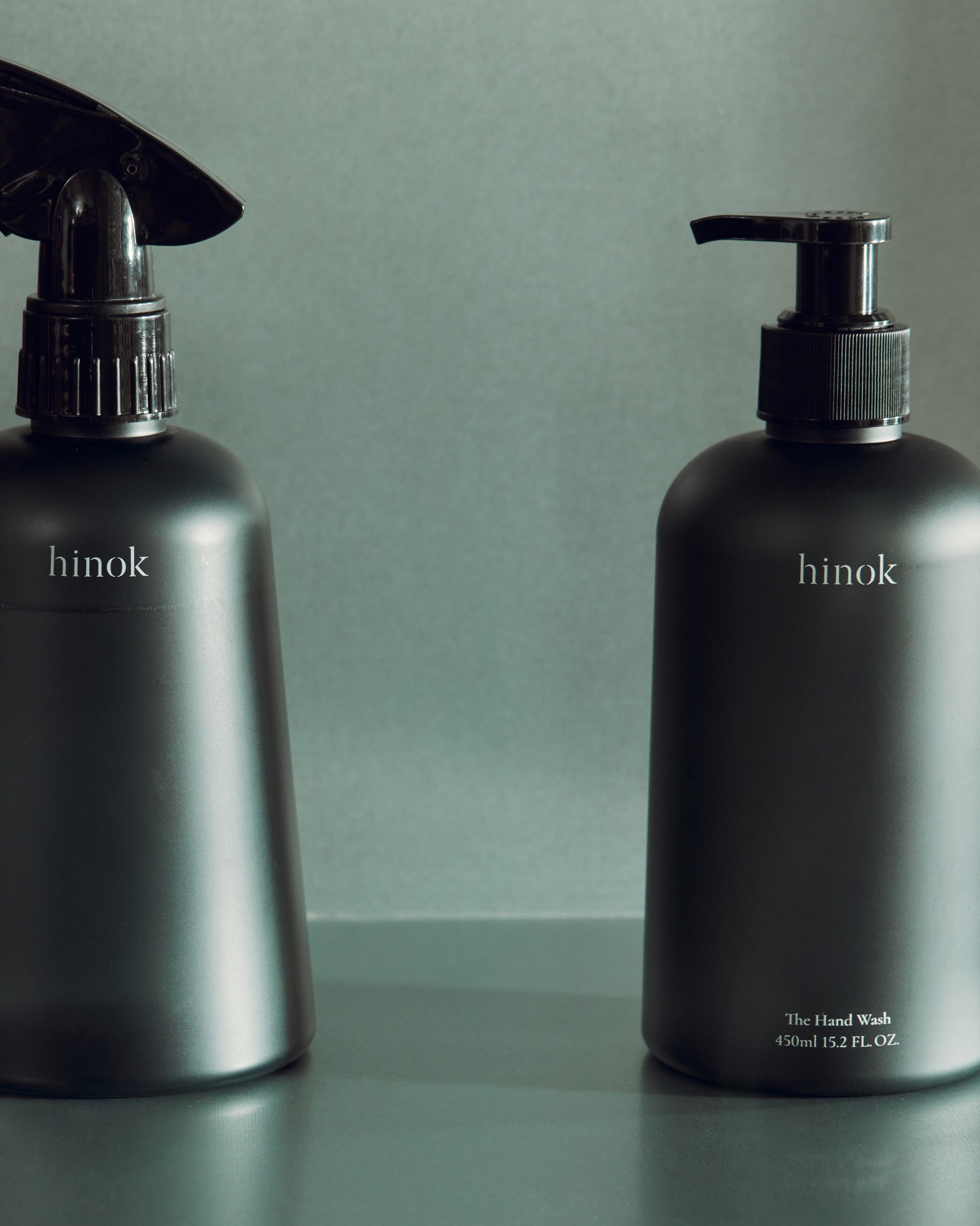 Close-up of The Spray bottle and The Hand Wash against a muted green background